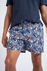 Short de baño con cintura elástica y cordón ajustable, confeccionado en tela ligera de secado rápido. Presenta un estampado botánico integral en tonos amarillos, blancos y azules, con dos bolsillos delanteros y uno posterior.