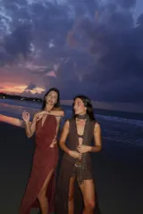 Falda larga tejida color marrón con brillo metálico, corte al cuerpo, abertura alta en la pierna y recortes laterales con cordones ajustables.