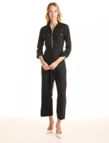 Enterito negro de la marca Sharagano, con escote en V y solapa. Presenta cierre frontal, bolsillos aplicados en la parte delantera, mangas largas con presilla y botón para regular el largo, y lazo de ajuste en la cintura.