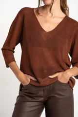 Sweater de punto con acabado brillante, cuello en V y mangas tres cuartos. Presenta un diseño holgado y tejido traslúcido.
