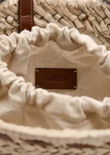Bolso de mano y bandolera de fibra natural trenzada, color beige, con detalles en cuerina marrón y aplique metálico dorado en el frente. Cuenta con doble asa corta y correa larga desmontable.