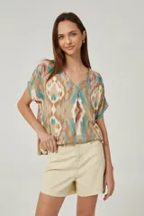 Blusa de lino con diseño estampado multicolor en tonos tostado, turquesa y rosado, corte holgado, mangas cortas y escote en V.