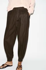 Pantalón jogger de tiro bajo color marrón, con cintura elástica ajustable con cordón, bolsillos delanteros y puños elásticos en los tobillos.