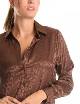 Camisa de satén labrado color marrón con estampado animal print tonal. Presenta cuello con solapa, manga larga y cierre frontal con botones.