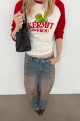 Camiseta de manga larga con cuello redondo, corte regular fit. Color blanco con mangas raglán rojas. Estampado frontal de Kermit the Frog y el texto "Kermit the Frog" en rojo.