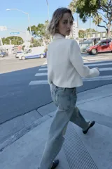 Blazer corto blanco de cuello solapa y manga larga con hombreras. Presenta un cierre frontal cruzado con dos botones dorados.