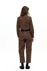 Pantalón de pana con corte barrel, tiro medio y estampado tipo tapiz en tonos marrones y negros. Cuenta con cierre frontal, pasacintos y bolsillos laterales y traseros.