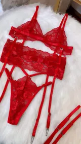 Conjunto de lencería de cuatro piezas en color rojo, confeccionado en encaje. Incluye bralette, tanga, portaligas y ligas regulables con enganches desmontables.