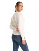 Buzo de tejido fino color blanco, con escote redondo decorado con un collar fijo de perlas y strass. Presenta mangas largas con un leve frunce en los hombros y puños acanalados.