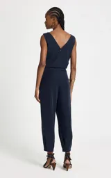 Pantalón sastrero de corte recto en color azul marino, con cintura media y detalle de cinturón de cadena metálica extraíble. Presenta un largo crop y acabado pespunteado.