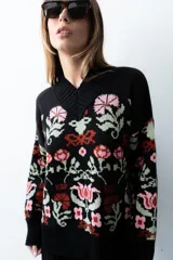 Buzo tejido de algodón negro con diseño jacquard de flores multicolor, cuello en V y mangas largas.