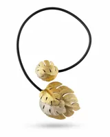 Collar Leaves inspirado en formas orgánicas, con estructura circular de cuero negro y diseño escultórico de hojas en tonos dorado y plateado.