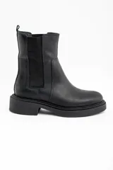 Bota tipo Chelsea de cuero negro, con paneles elásticos laterales y suela de goma con plataforma baja.