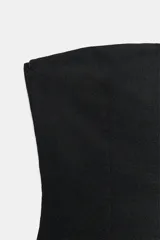 Top negro strapless de tejido elástico, con escote recto y aberturas laterales en el bajo.