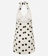 Vestido corto blanco con estampado de lunares negros, escote en V y espalda descubierta con tiras ajustables en el cuello.