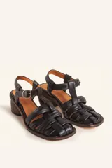 Sandalias de cuero color negro con diseño de tiras cruzadas tipo huarache, tira ajustable con hebilla metálica en el empeine y taco cilíndrico de madera.