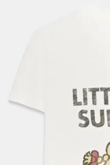 Camiseta de algodón flamé color blanco, de corte regular con cuello redondo y manga corta. Presenta un estampado frontal con texto y gráfico del personaje Little Miss Sunshine.