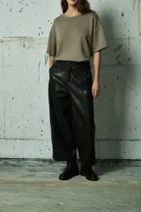 Pantalón de cuero sintético negro de corte ancho y tiro alto, con costuras verticales decorativas en el frente y cierre frontal con botón.