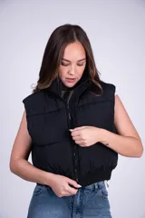 Chaleco puffer corto color blanco, con cuello elevado y cierre frontal. Cuenta con diseño acolchado y bolsillos laterales.