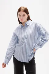 Camisa de algodón con diseño de rayas verticales finas en tonos neutros, corte holgado, cuello camisero y cierre frontal con botones.
