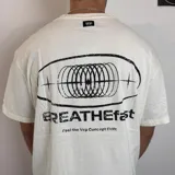 Remera negra de corte regular con estampa gráfica en la espalda que incluye un diseño circular abstracto y el texto BREATHEfast.
