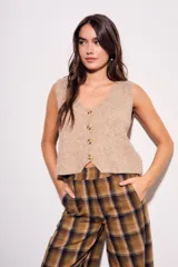 Chaleco de punto sin mangas, color camel jaspeado, con escote en V y cierre frontal de tres botones marrones.