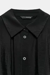 Camisa de cuello solapa y manga corta, confeccionada en tejido con textura satinada. Presenta cierre frontal con botones y bajo acabado con lazada en el delantero.