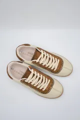 Zapatillas bajas de cuero color crema con detalles en marrón y cordones blancos.