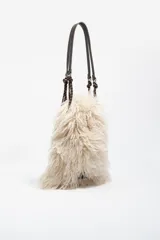 Bolso de hombro con estructura blanda, confeccionado en poliéster con acabado de pelo largo en color beige. Presenta asas de cuero marrón y detalles de cordones trenzados. Incluye cierre de cordón y bolsillo interior.