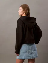 Buzo negro con capucha y cierre frontal completo, confeccionado en suave fleece de mezcla de algodón y poliéster. Presenta el logo Archive de Calvin Klein bordado en el pecho, bolsillos laterales y un corte regular.