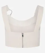 Blusa cropped de sastrería color beige, con escote corazón, breteles anchos con aros metálicos y cierre en la espalda.