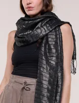 Pashmina rectangular de caída fluida, color negro con hilos metalizados que forman líneas horizontales plateadas y terminación de flecos finos en los extremos.