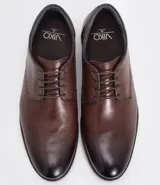 Zapato de vestir acordonado color marrón oscuro, de cuero, con suela blanca y detalles de costuras.