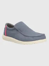 Zapato slip-on Hush Puppies modelo Gordon, de lona color azul grisáceo con suela de EVA moteada. Presenta detalles en color fucsia en el talón y forrería interior a rayas.