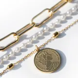 Collar triple dorado: cadena gargantilla de eslabones pequeños, cadenita media con perlas y cadena larga con dije circular de la Reina Isabel.