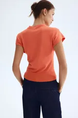 Top en punto fino tupido color naranja con cuello elevado corto y manga japonesa, con remate acanalado en el bajo.