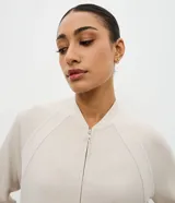 Campera deportiva de cuello alto con cierre frontal, mangas largas con puños elásticos y diseño de corte raglán. Presenta un estilo minimalista y funcional con cintura ajustable.
