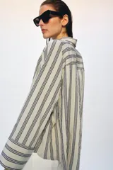 Camisa de corte oversize confeccionada en mezcla de viscosa, con estampado de rayas verticales. Presenta cuello solapa, cierre frontal con botones y mangas largas con puños amplios.