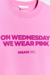Camiseta de manga larga en color rosado con cuello redondo. Presenta un estampado frontal con la frase 'On Wednesday we wear pink' y el logo de Mean Girls en color fucsia.