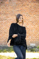 Buzo de textura tipo peluche en color negro, con diseño oversize, cuello amplio y mangas largas acampanadas.