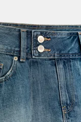 Falda mini de jean con diseño de tablas, tiro medio, bolsillos delanteros y cierre frontal con botones.
