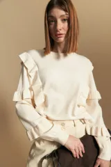 Sweater negro de manga larga, tejido suave y caída liviana, con volados en el delantero y mangas. Silueta recta.