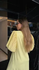 Vestido largo color amarillo pálido, con escote en V, mangas cortas abullonadas con detalle de calado y ruedo con volantes y calado.