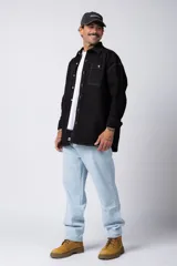 Camisa de manga larga estilo sobrecamisa, color negro, con corte oversize, cuello clásico, cierre frontal con botones y bolsillo frontal en el pecho.