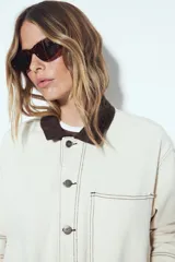 Sobrecamisa tipo Barn Jacket color marrón oscuro, de algodón con elastano, silueta relajada y estructura firme. Presenta cierre frontal con botones metálicos, cuello negro, bolsillos aplicados y pespuntes visibles.