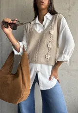 Chaleco de punto color beige con escote en V, diseño de trenzas verticales y tres flores tejidas en relieve.