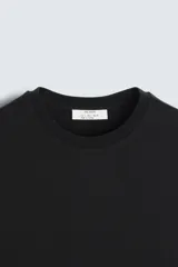 Camiseta de corte regular confeccionada en tejido de algodón compacto, con cuello redondo y manga corta.