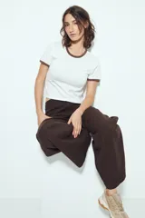 Remera cropped blanca de manga corta, con cuello redondo y terminaciones en contraste de color marrón en cuello y mangas. Inspirada en los clásicos de los años 80.