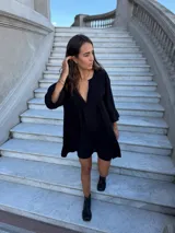 Vestido corto de fibrana color negro, con escote en V, tablas decorativas en el frente, mangas con volados y ruedo con volado. Diseño holgado y liviano.