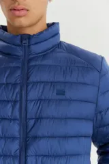 Campera puffer acolchada de color azul marino, con cuello alto y cierre frontal completo. Diseño ligero y versátil, ideal para media estación.